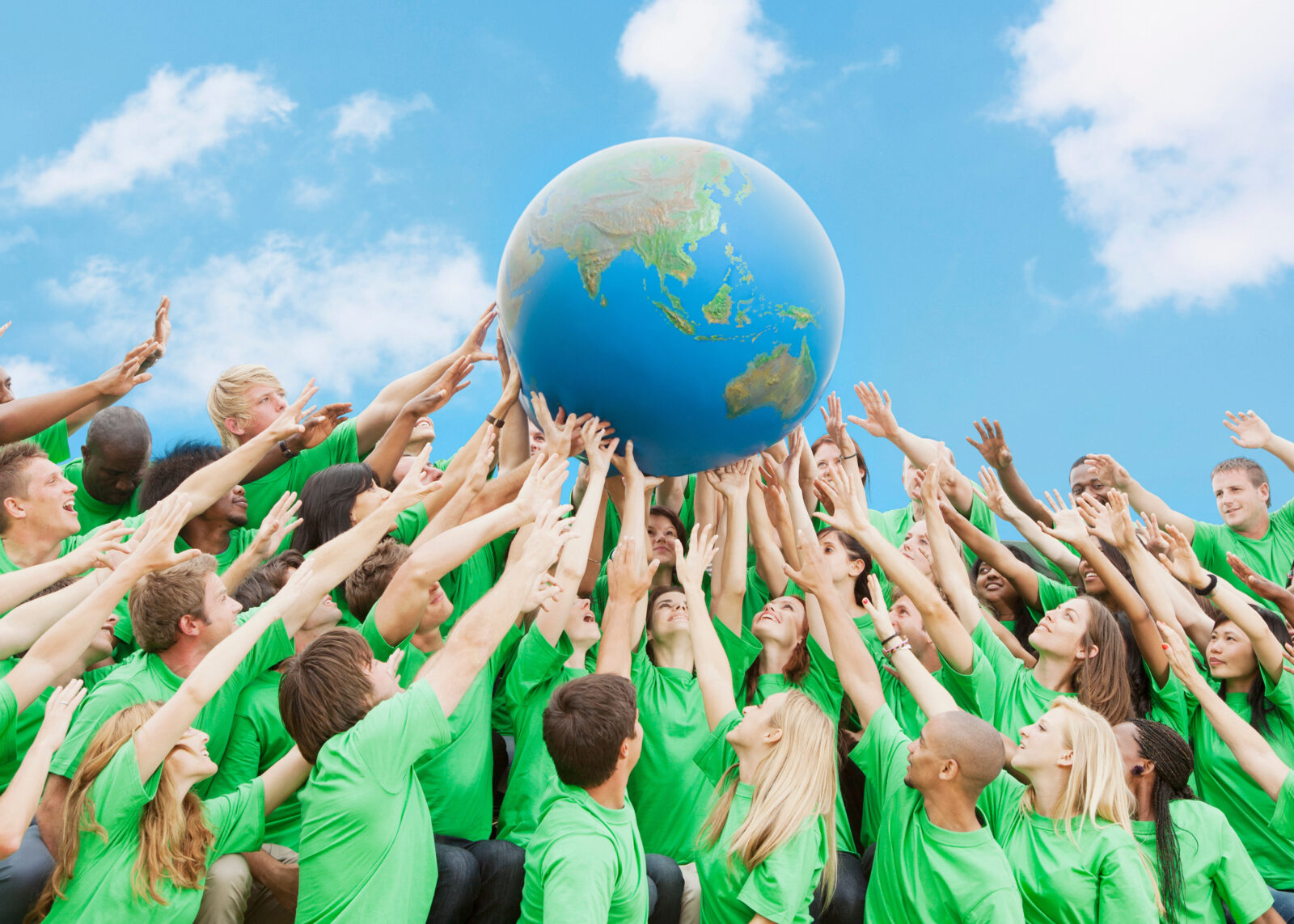 Team in green t-shirts lifting globe overhead